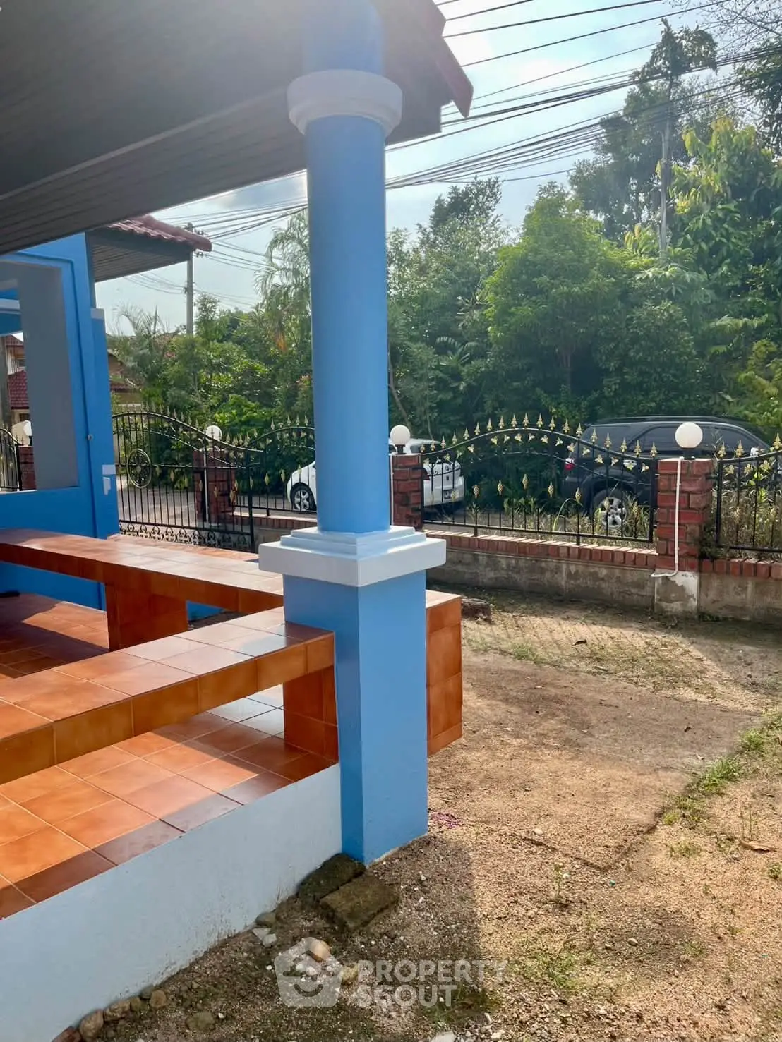 Charming blue-painted exterior with tiled porch and lush greenery, perfect for a serene living experience.