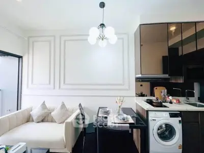 Modern living room with elegant kitchen and washing machine, featuring chic decor and stylish lighting.
