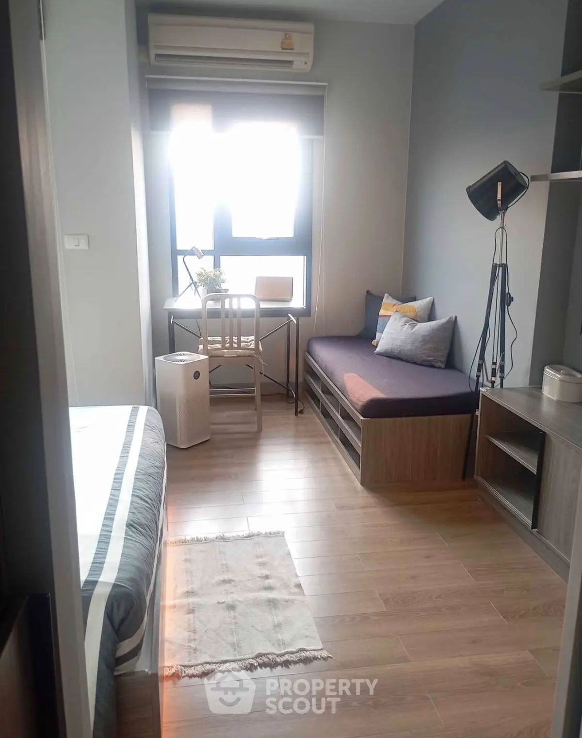 Cozy bedroom with modern decor and natural light, featuring a stylish seating area and workspace.