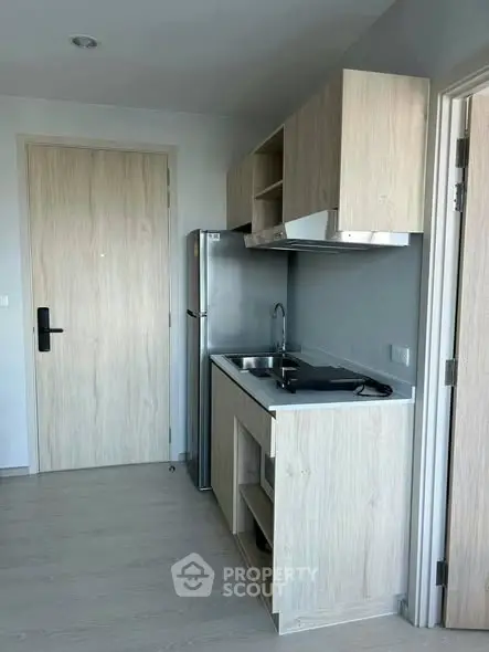 Modern compact kitchen with sleek cabinetry and stainless steel appliances in a stylish apartment.
