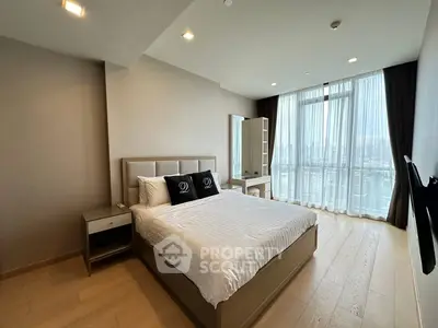 Spacious modern bedroom with large window and city view, featuring elegant decor and natural light.