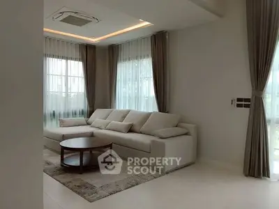 Elegant living room with modern sofa and large windows, perfect for relaxation.