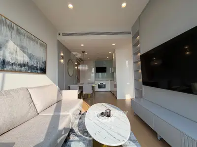 Modern living room with sleek design and open kitchen layout, featuring a large TV and stylish decor.