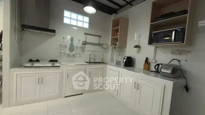 Modern kitchen with white cabinets, gas stove, and microwave in a sleek design.