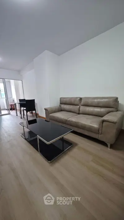 Spacious living room with modern sofa and sleek coffee table in a bright apartment.