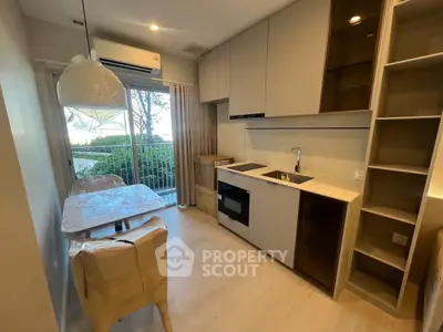Modern kitchen with open layout and dining area, featuring sleek cabinetry and large window view.