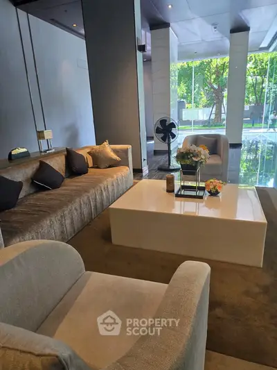 Luxurious living room with modern furniture and large windows offering a serene garden view.