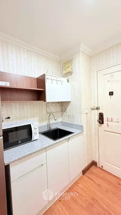 Compact kitchen with modern appliances and stylish cabinetry in cozy apartment.