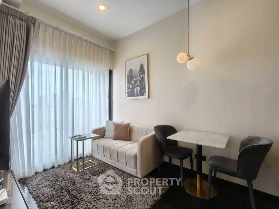 Modern living room with elegant decor, featuring a cozy sofa, chic dining set, and large window with sheer curtains.