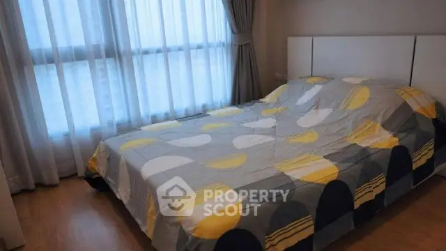 Cozy bedroom with large window and modern decor in a bright apartment.