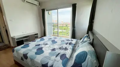 Modern bedroom with large window and city view, featuring stylish bedding and sleek furniture.