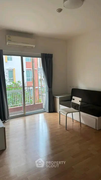 Bright living room with wooden flooring and balcony access in modern apartment.