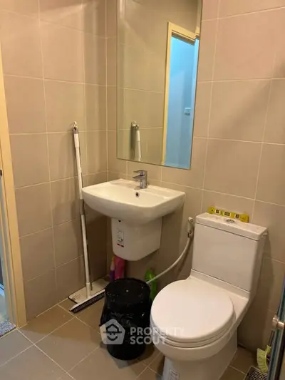 Modern bathroom with sleek fixtures and neutral tiles, featuring a compact design ideal for urban living.