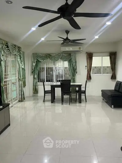 Spacious living room with elegant curtains and modern ceiling fans, perfect for family gatherings.