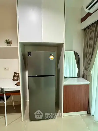 Modern kitchen corner with sleek fridge and stylish cabinetry in a cozy apartment.