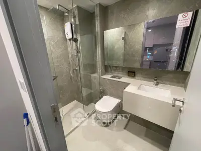 Modern bathroom with sleek design, featuring a glass shower enclosure and wall-mounted toilet.
