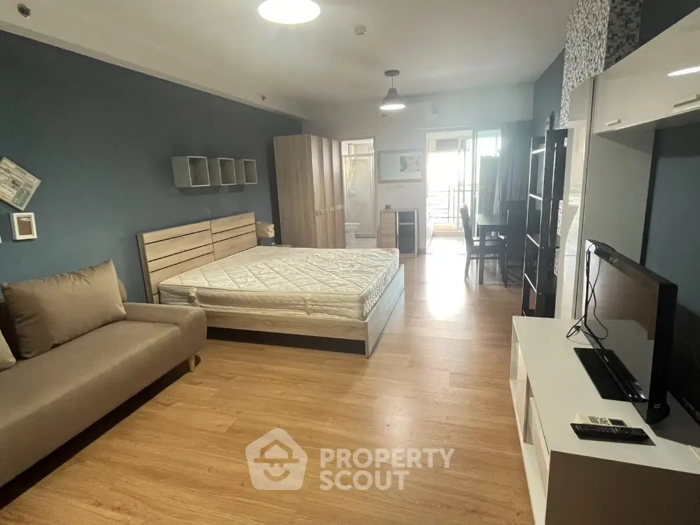 Spacious modern bedroom with wooden flooring and balcony access