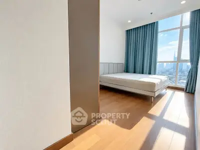 Spacious bedroom with large window offering stunning city views and abundant natural light.