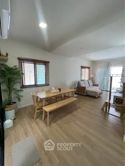 Spacious living room with modern decor and natural light, featuring wooden flooring and stylish furniture.