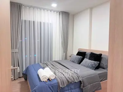 Modern bedroom with cozy bedding and elegant curtains in a stylish apartment.