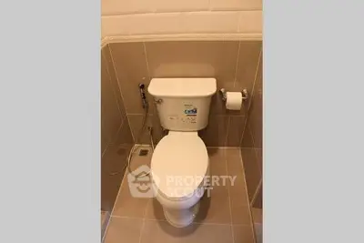 Modern bathroom with sleek toilet and beige tiles, perfect for a contemporary home.