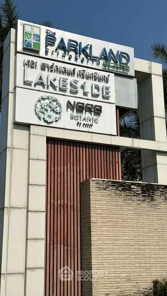 Modern real estate development sign for Parkland Lakeside with lush surroundings.