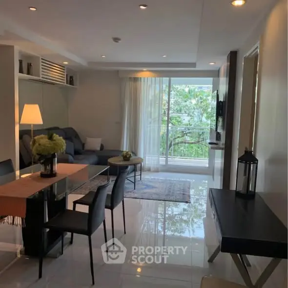 Modern living room with elegant decor and large windows opening to a lush green view.