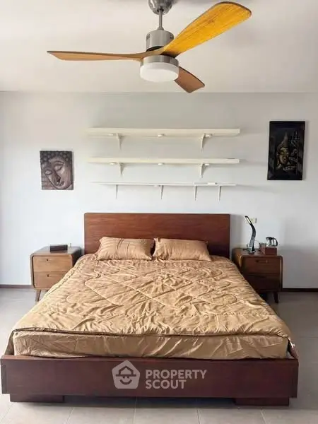 Modern bedroom with wooden bed and ceiling fan, featuring minimalist decor and wall art.