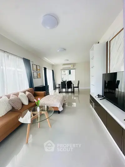 Spacious modern living room with elegant decor and dining area, featuring sleek furniture and ample natural light.