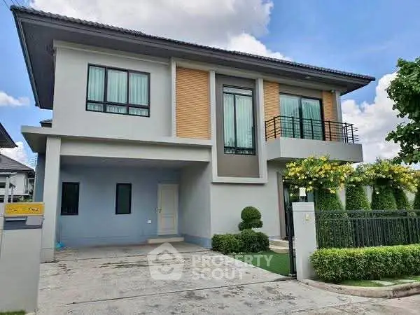Modern two-story house with landscaped garden and spacious driveway.