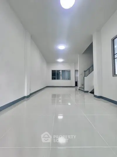 Spacious modern interior with sleek white tiles and ample natural light, perfect for versatile living space.