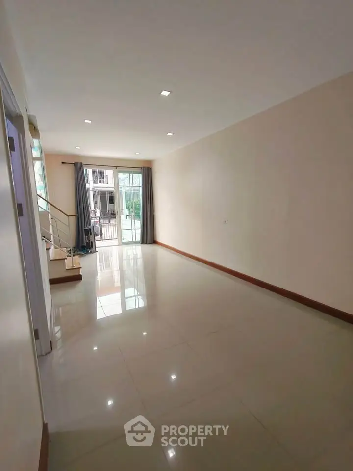 Spacious empty living room with large windows and glossy tiled floor