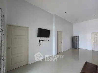 Spacious modern living room with wall-mounted TV and sleek refrigerator.