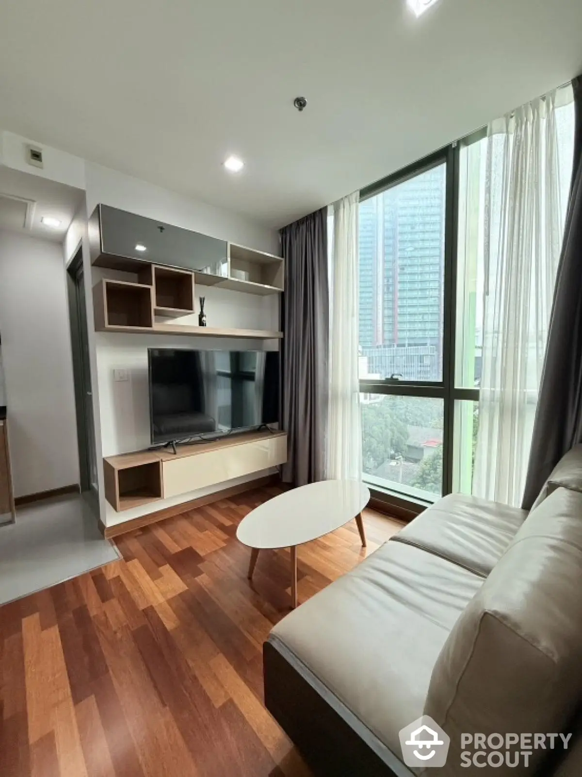 Modern living room with large window and stylish furniture in high-rise apartment.