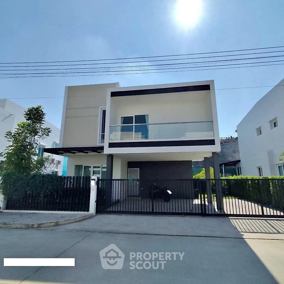 Modern two-story house with sleek design and spacious balcony under clear blue sky.
