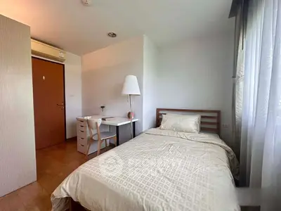 Cozy bedroom with natural light, wooden flooring, and modern furniture.