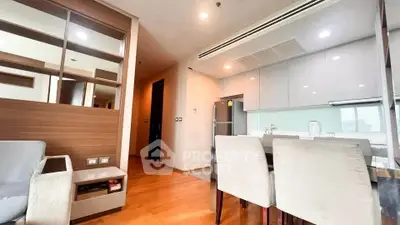 Modern open-plan living and dining area with sleek kitchen in stylish apartment.