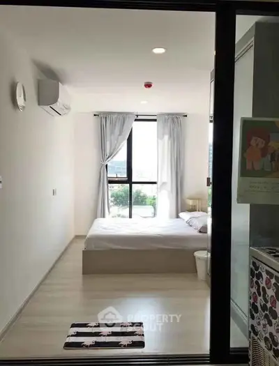 Modern bedroom with large window and minimalist decor in a bright apartment.