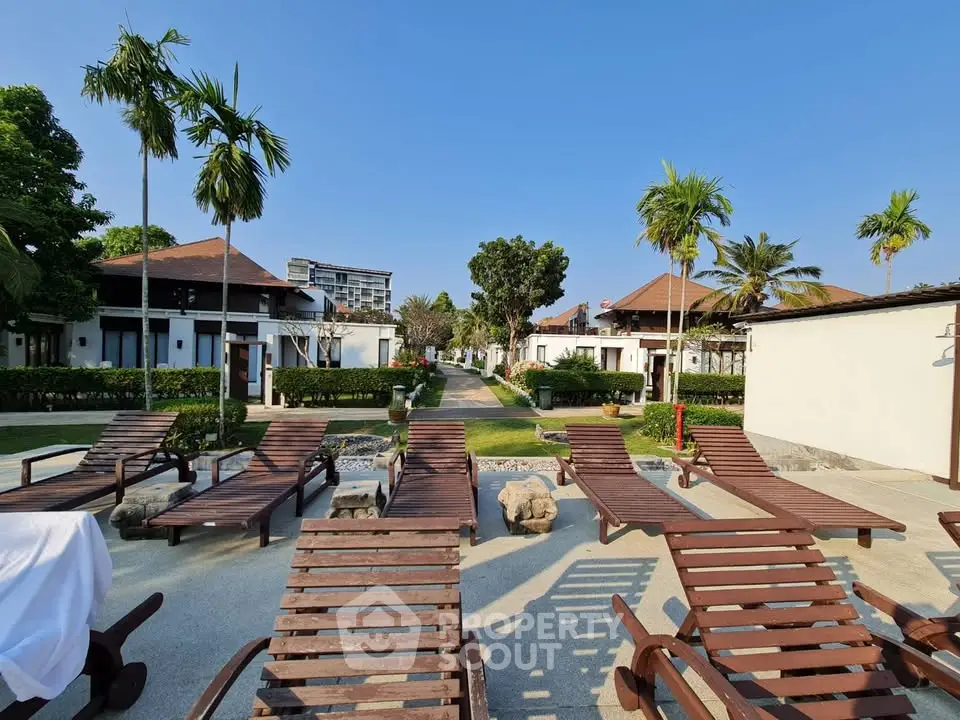 Luxurious resort-style outdoor area with sun loungers and lush greenery, perfect for relaxation and leisure.