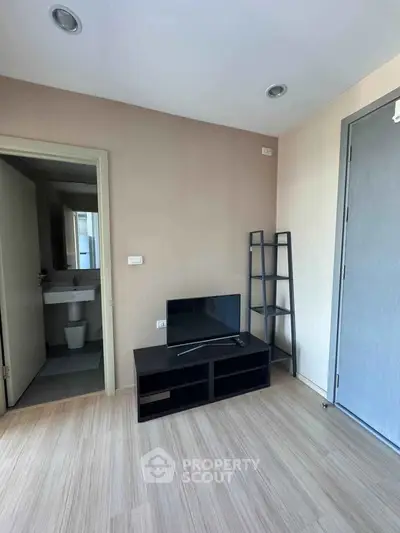 Modern living room with TV stand and open bathroom view, featuring sleek wooden flooring.