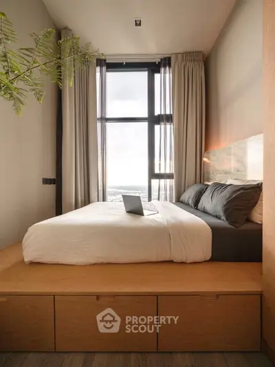 Modern bedroom with large window and stylish decor, featuring a cozy bed and natural light.