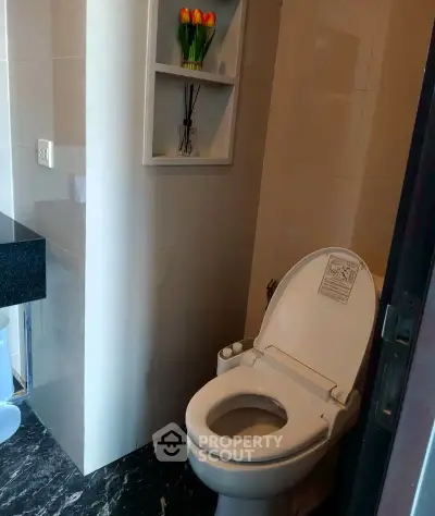 Modern bathroom with sleek toilet and elegant black marble flooring.