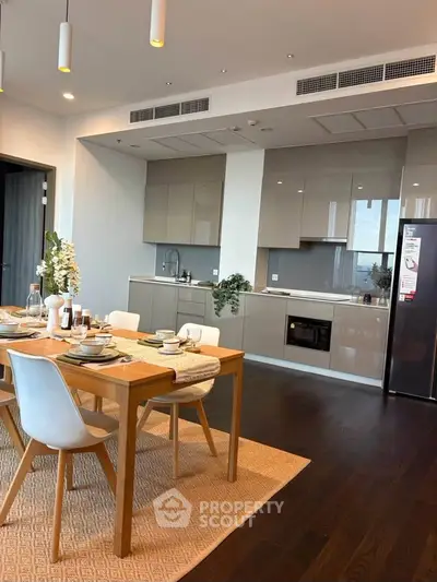 Modern kitchen with sleek cabinetry and dining area, featuring contemporary decor and ample natural light.