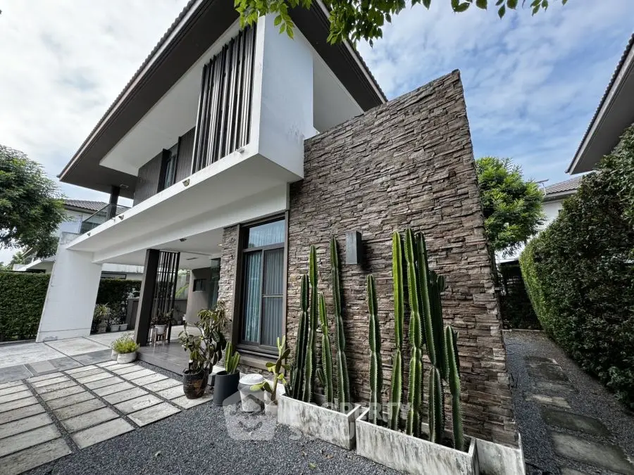 Modern two-story house with stone facade and lush greenery