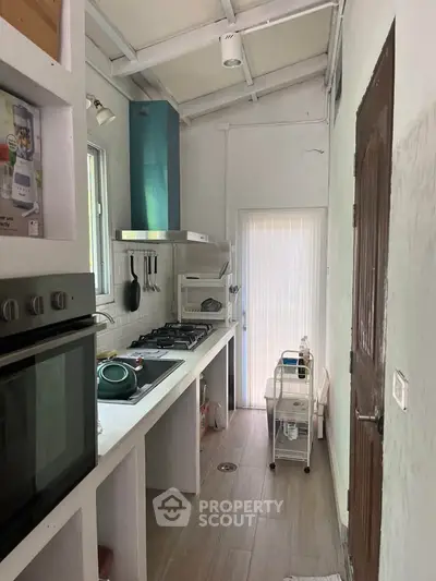 Charming compact kitchen with modern gas stove and oven, ideal for efficient cooking in cozy spaces.