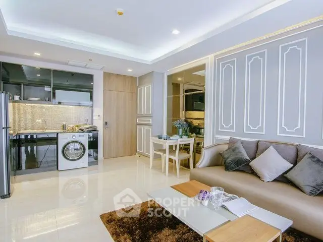 Modern open-layout living room with kitchen featuring washing machine and stylish decor.