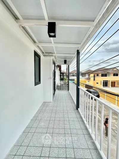 Spacious balcony with tiled flooring and modern railing offers street view in residential area.