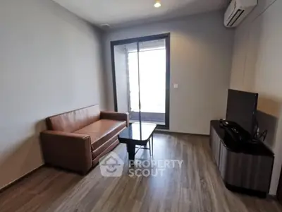 Modern living room with sleek furniture and large window offering natural light.