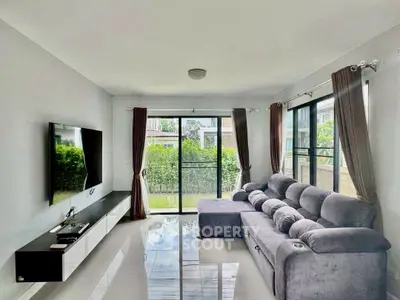 Spacious living room with modern decor and large windows overlooking greenery.