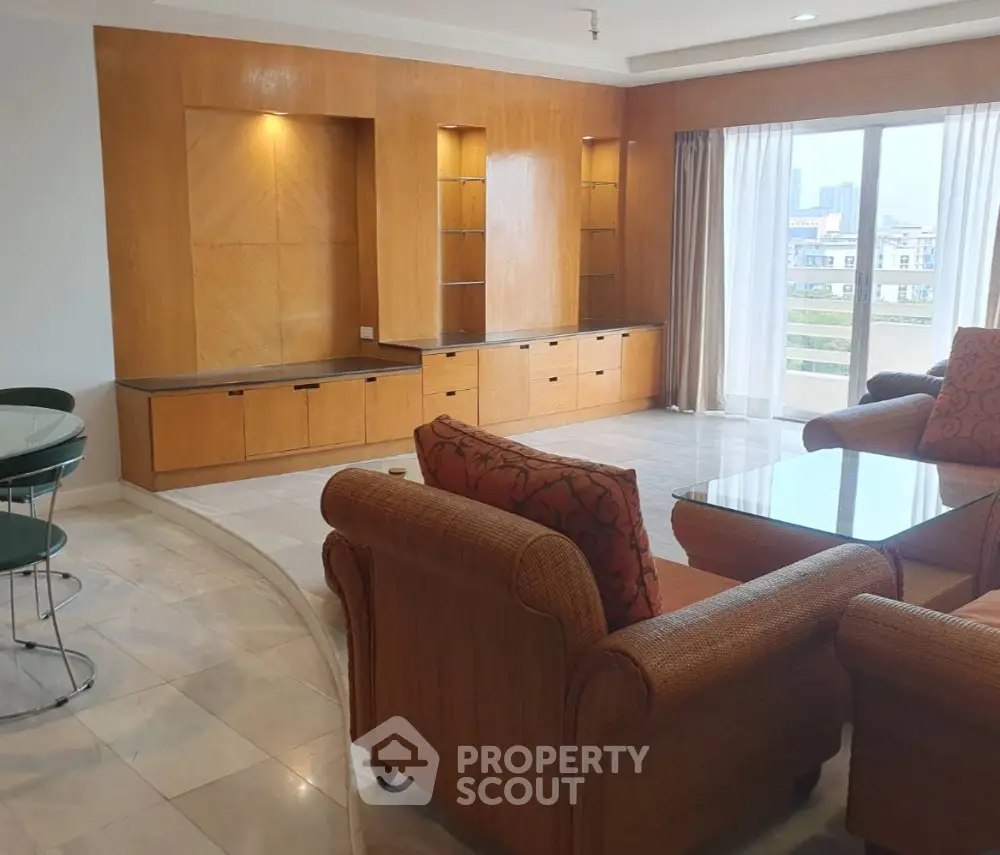 Spacious living room with elegant wooden cabinetry and large windows offering city views